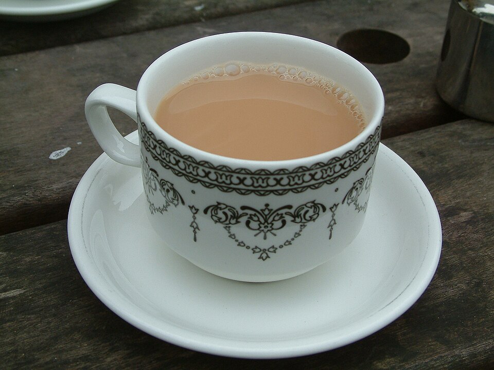 A cup of black tea with milk in a patterned white china cup and saucer.